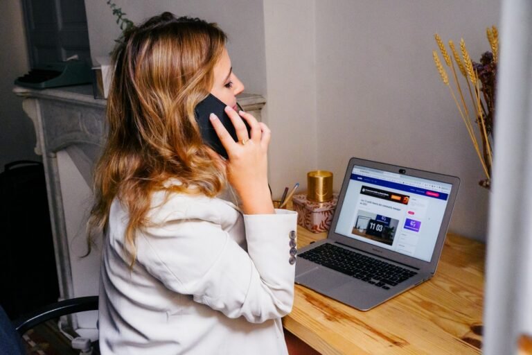 Woman at her desk with a laptop and phone, ready to help with your inquiry